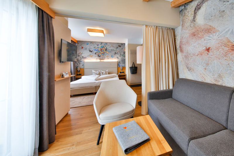 Hotelzimmer mit weißer Bettwäsche und einem Wandtattoo.